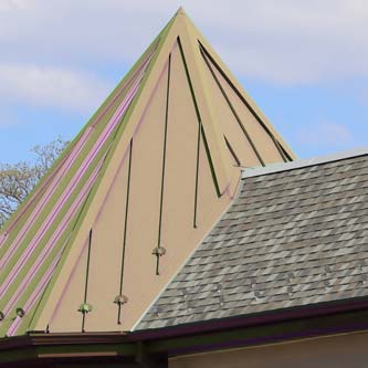 Teepee style roof with shingle roof adjacent.